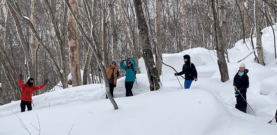 米子不動滝のスノーシューハイキングツアーで雪が覆う林間を歩く