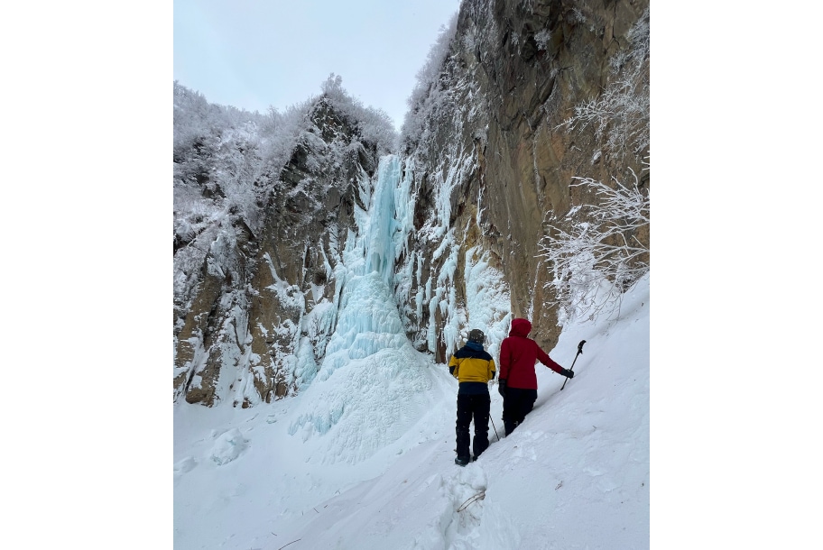 権現滝の近くで滝を見上げるスノーシューハイキングツアーの参加者