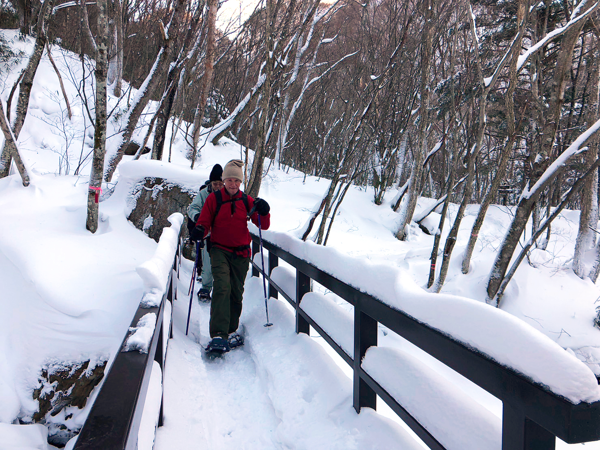 スノーシューハイキングコースの途中にある橋を渡る参加者