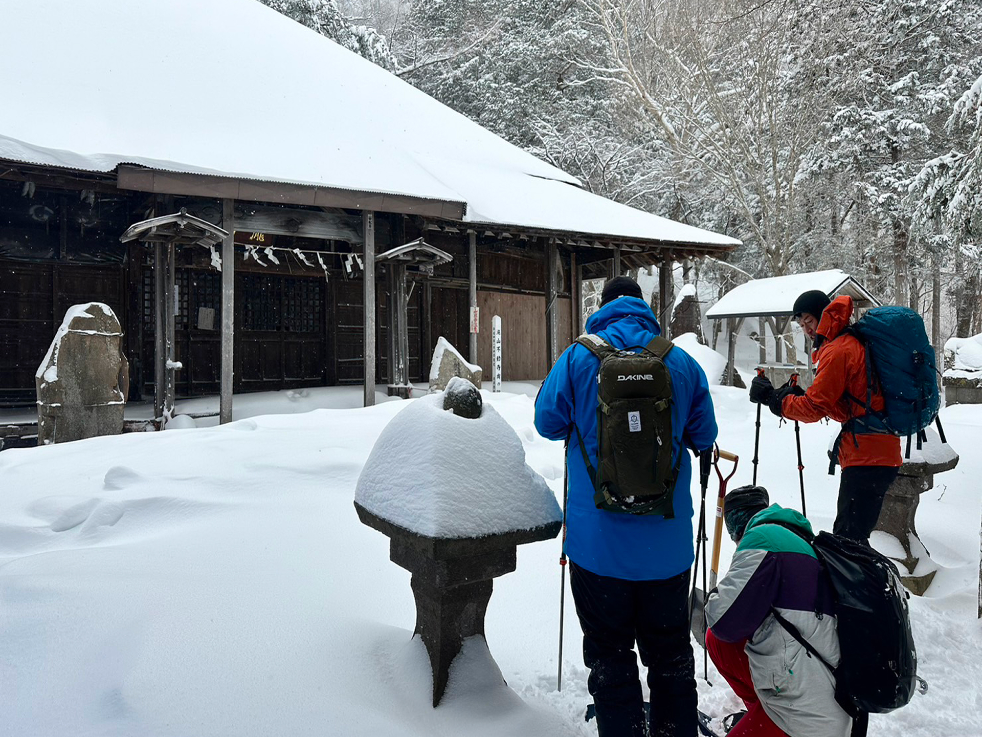 雪の中の米子不動寺の奥ノ院に参拝する米子不動滝スノーシューハイキングツアーの参加者